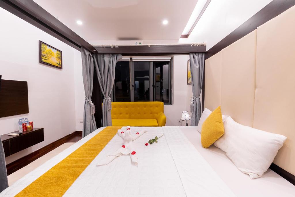 a bedroom with a large white bed with a yellow couch at Hanoi Cozy Legend Hotel in Hanoi