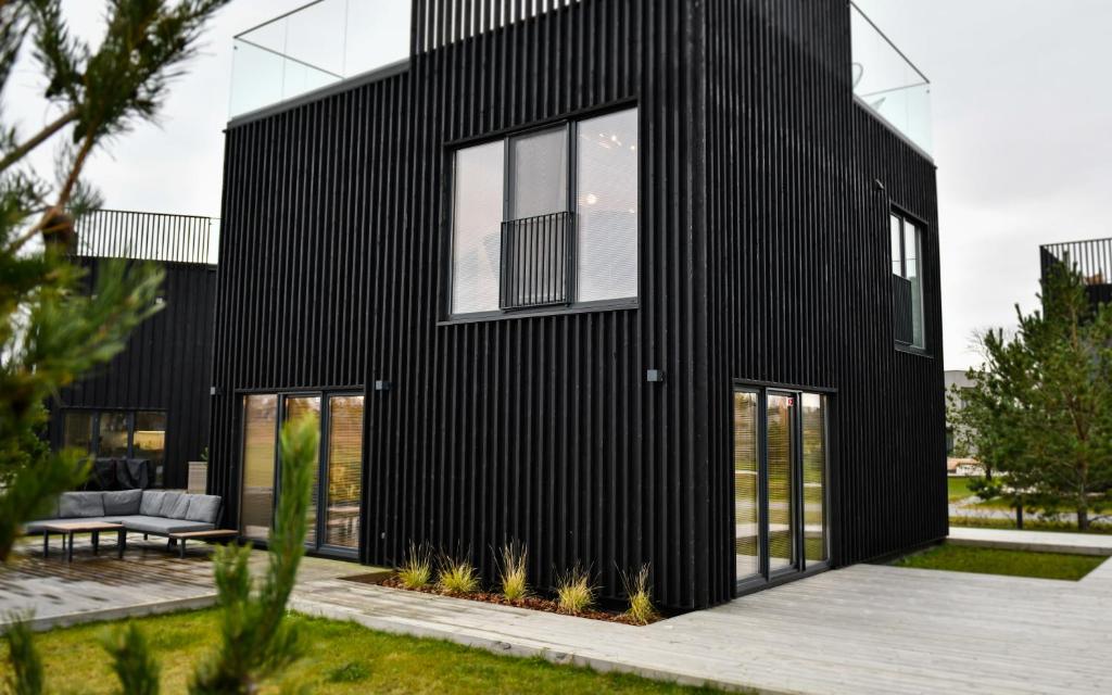 Casa negra con ventanas grandes en Namo nuoma Svencelėje, en Svencelė