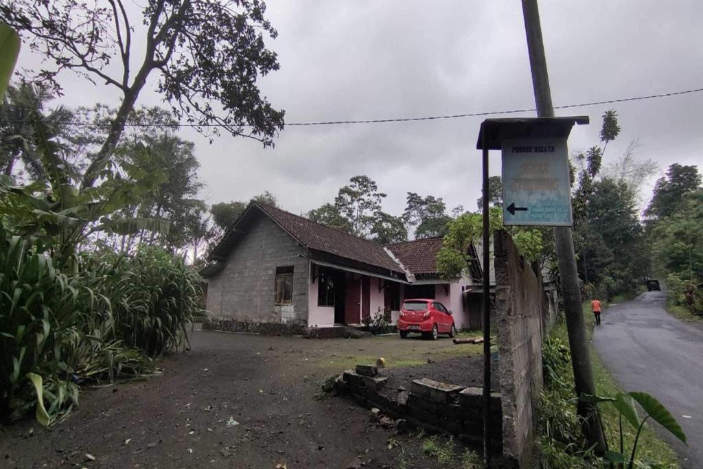 ein Haus mit einem roten Auto, das davor geparkt ist in der Unterkunft OYO 93395 Pondok Wisata Sekar Kemuning in Yogyakarta