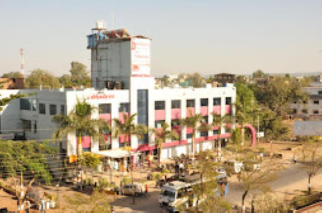 un gran edificio blanco con palmeras delante en Hotel Abhashree ,Madhya Pradesh, en Betūl