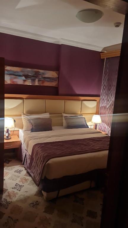 1 dormitorio con 1 cama grande y paredes moradas en شقق فندقية التلال, en La Meca