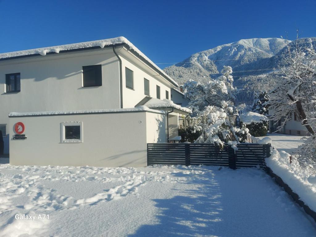 ein weißes Haus im Schnee mit Bergen im Hintergrund in der Unterkunft Unicorn Apartment in Nüziders