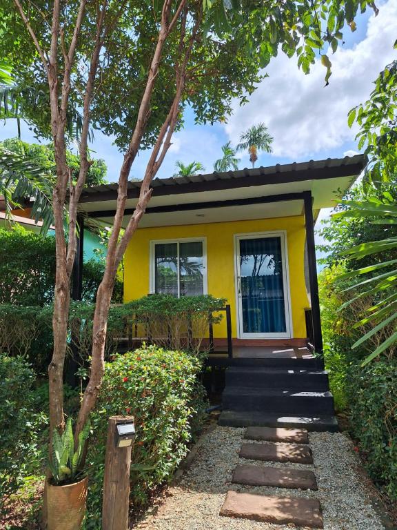 a yellow house with a pathway leading to it at Lanta Happy House in Ko Lanta