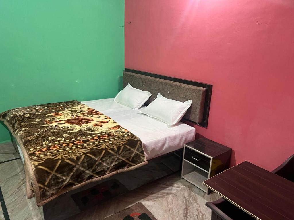 a bedroom with a bed and a pink wall at Indiana home stay in Khajurāho