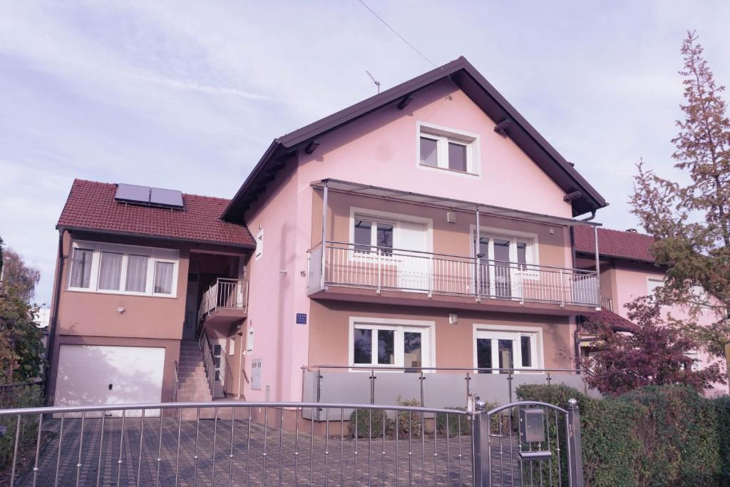 ein rosa Haus mit einem Tor davor in der Unterkunft Apartmani Jastreb in Jastrebarsko