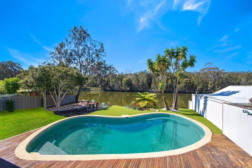 a swimming pool on a deck next to a backyard at Easygoing Poolside Relaxation on Wyong River in Tuggerah