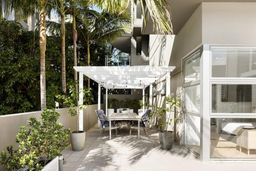 a patio with a table and chairs and palm trees at 'The Cordelia' Sweeping South Brisbane Style in Brisbane