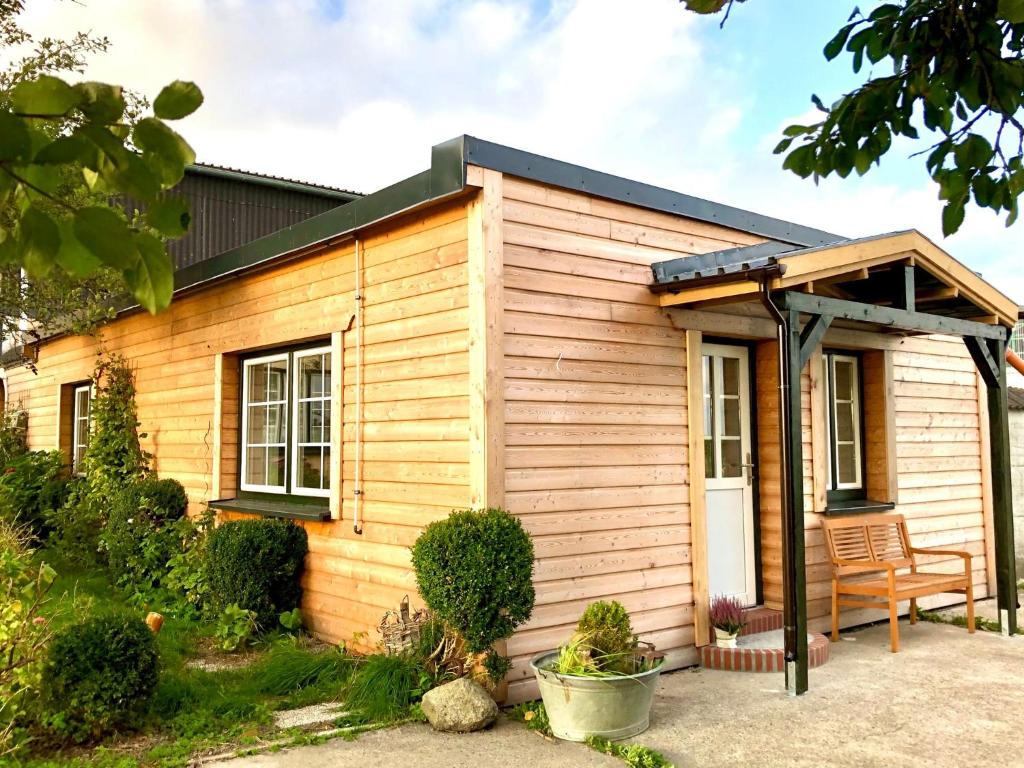 a wooden house with a bench in front of it at Appartement Huus Appelboom in Nordstrand