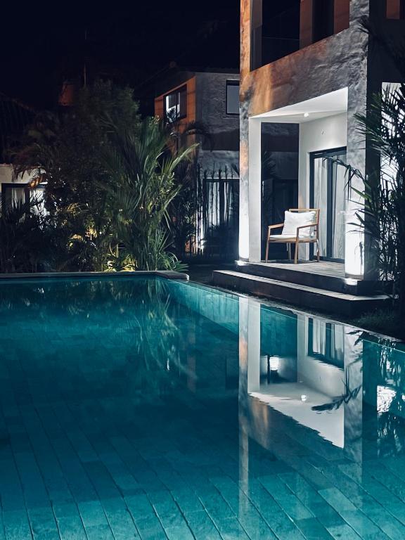 a swimming pool at night next to a building at HOLA villas & lofts Uluwatu in Uluwatu