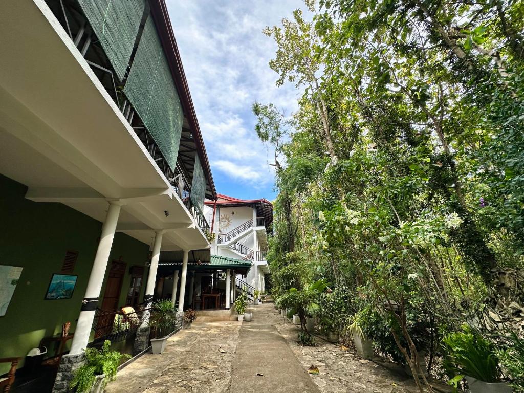 a building with a sidewalk next to a tree at Nature House in Udawalawe