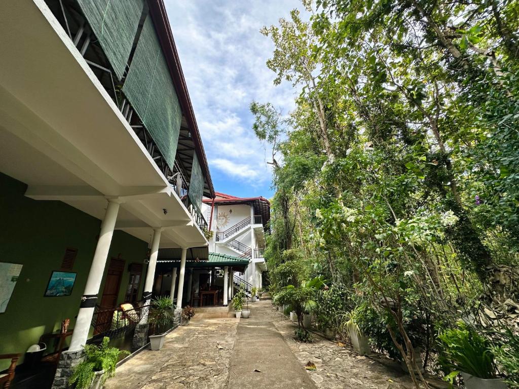 un bâtiment avec un trottoir à côté d'un arbre dans l'établissement Nature House, à Uda Walawe