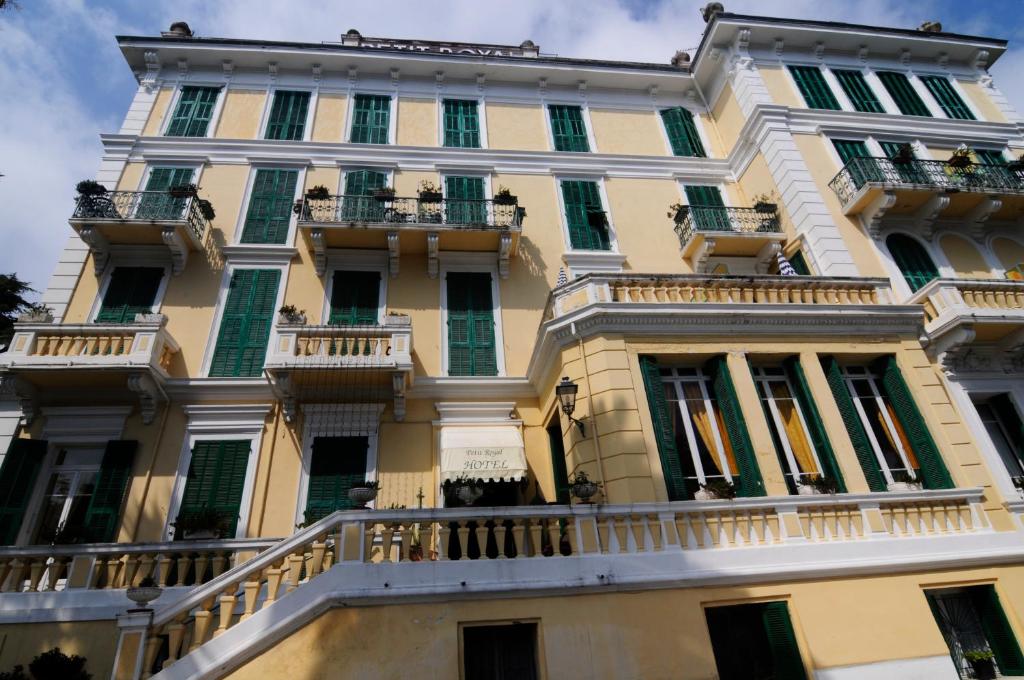 un grande edificio giallo con balconi e finestre di Hotel Petit Royal a Ospedaletti