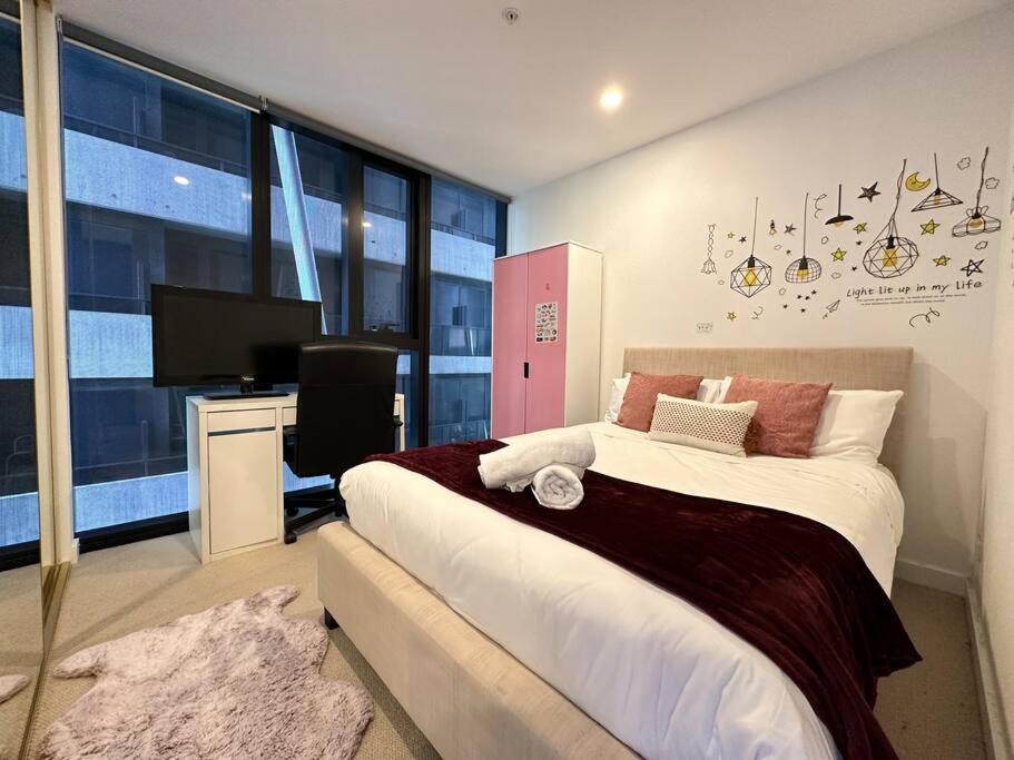 een slaapkamer met een bed, een bureau en een televisie bij Avant CBD Cozy & Spacious 2BR Residences in Melbourne