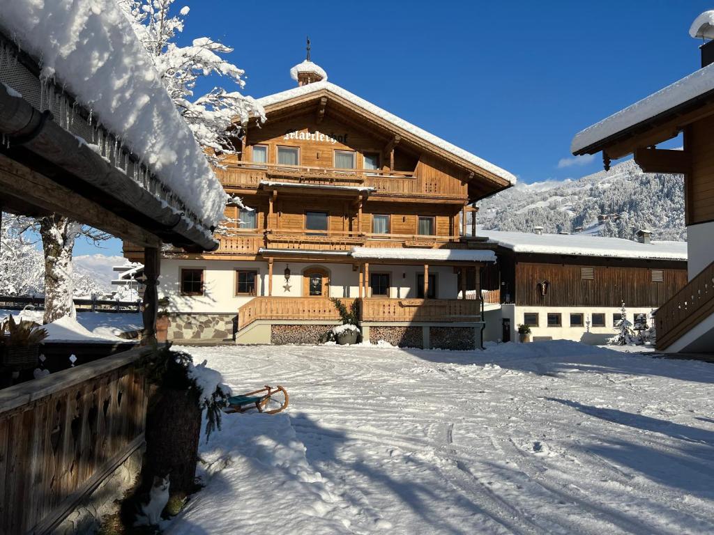 ein großes Holzgebäude mit Schnee auf dem Boden in der Unterkunft Martlerhof in Aschau