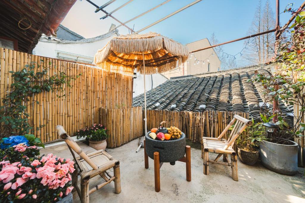 a patio with two chairs and an umbrella and a bowl of fruit at 2 Old Town Designer Chalet 200 year old house in Shanghai