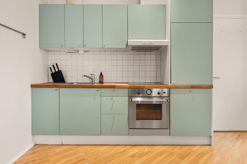 una cocina con armarios blancos y fregadero en Dinbnb Apartments I 500m to Bryggen, en Bergen