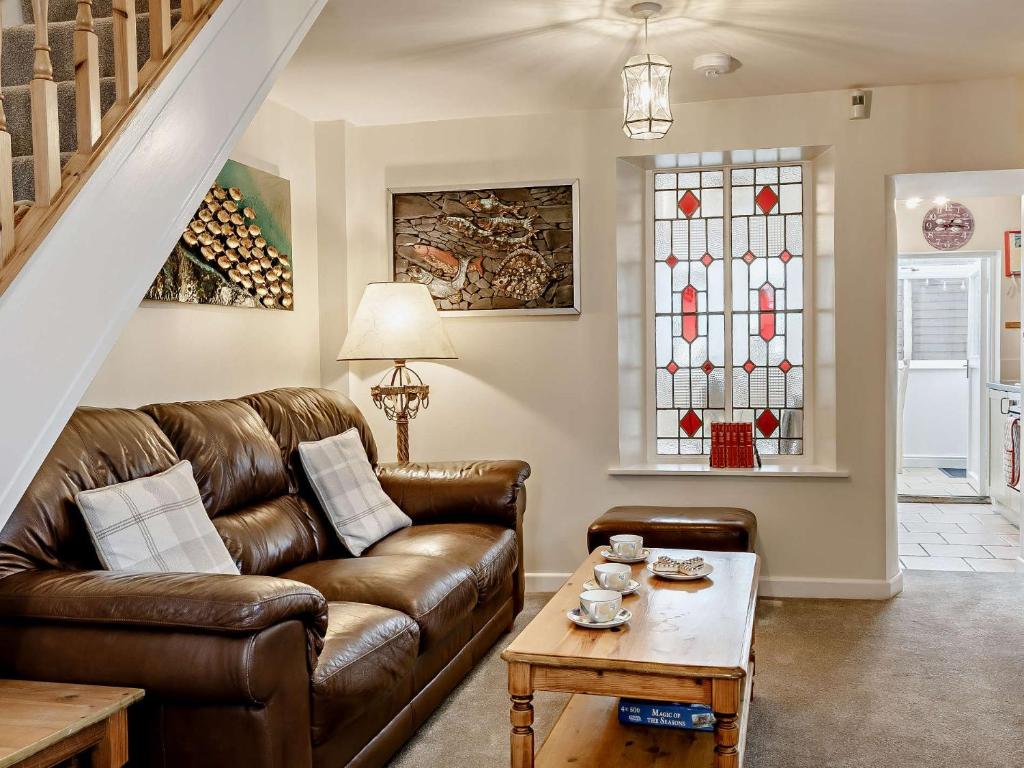 3 bed property in Brixham BX017 في بريكسهام: غرفة معيشة مع أريكة جلدية ونوافذ زجاجية ملطخة