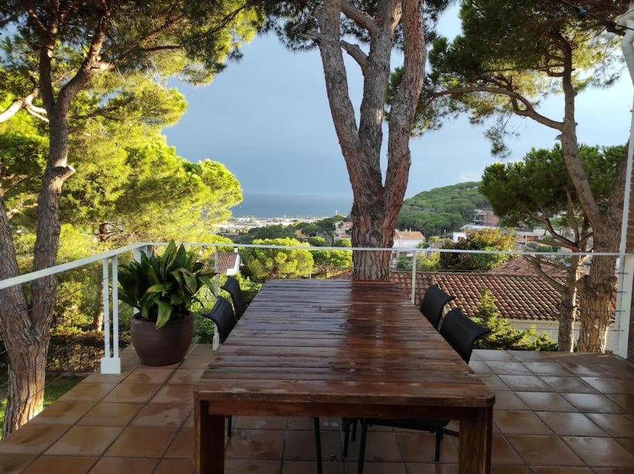 einen Holztisch auf einer Terrasse mit Bäumen und Aussicht in der Unterkunft Apartamento con magníficas vistas a 25 min de Barcelona in Premia de Dalt