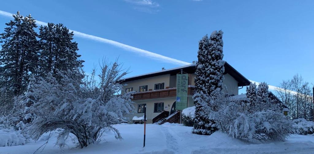 ein schneebedecktes Gebäude mit Bäumen davor in der Unterkunft Dorfpension Mariahilfberg in Gutenstein