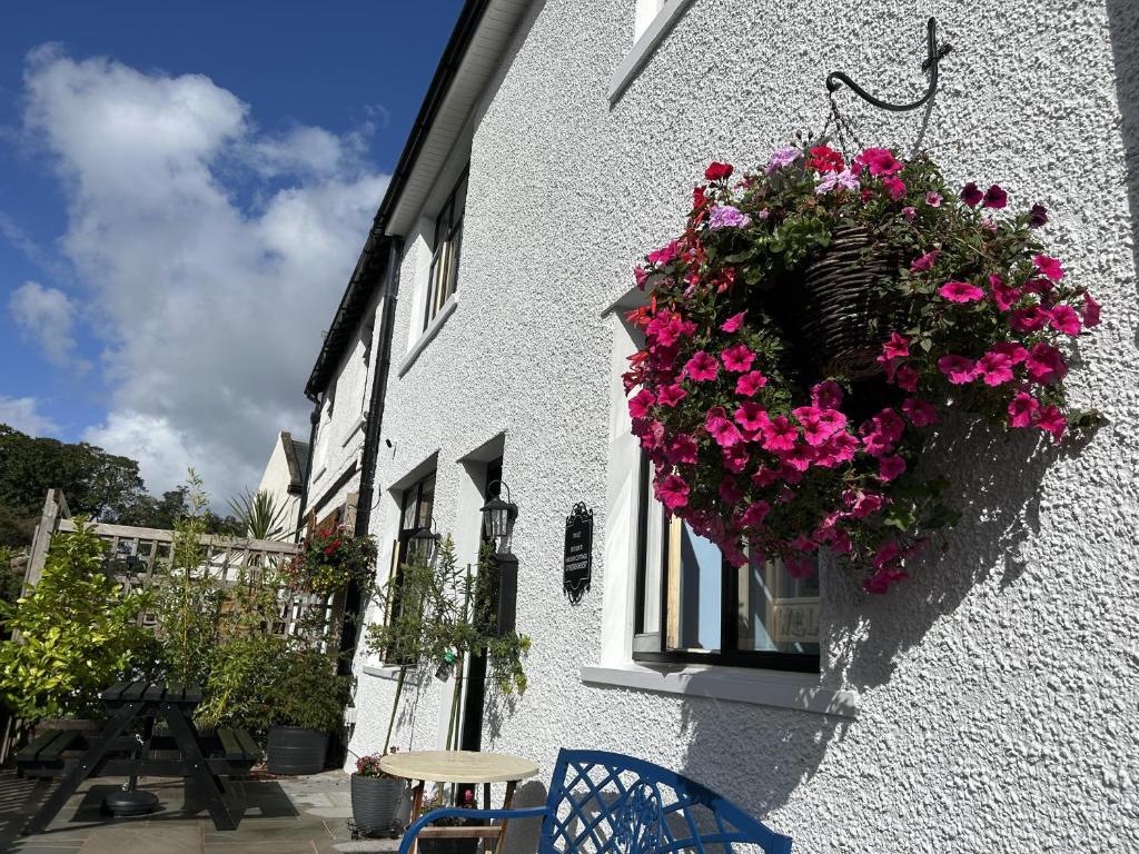 ein weißes Gebäude mit einem Korb mit rosa Blumen in der Unterkunft Historical Village Cottage - Pet Friendly in Heysham