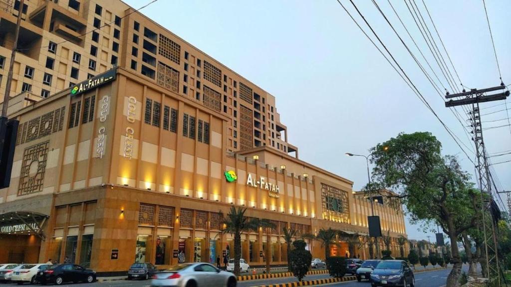 un grande edificio con macchine parcheggiate di fronte di 2BR Gold Crest Luxurious Residency Apartment BY AirHomes DHA Lahore a Lahore