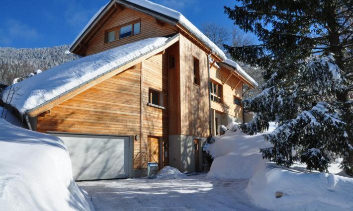 a wooden building with a garage in the snow at Maison d'hôtes Agathe et Sophie in Lans-en-Vercors