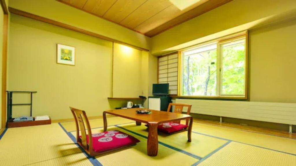Zimmer mit einem Tisch, Stühlen und einem Fenster in der Unterkunft Berjaya Hakkoda Ski Resort in Aomori