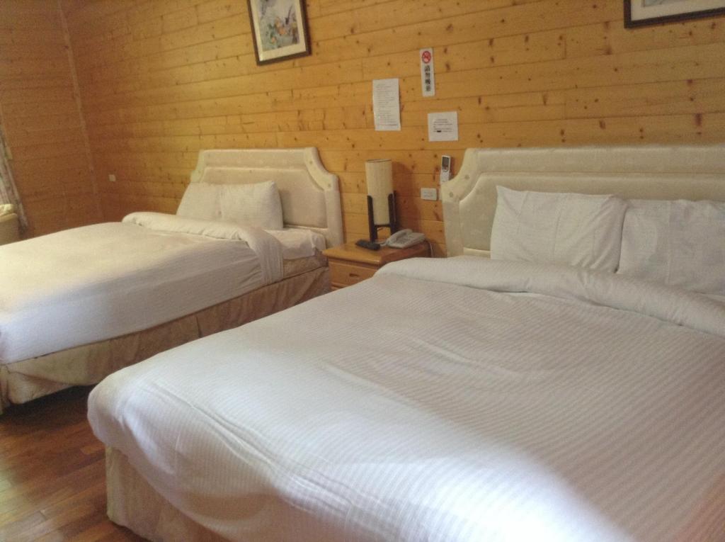 two beds in a hotel room with wooden walls at Bunbury Fruit Ranch B&amp;B in Ren&#39;ai