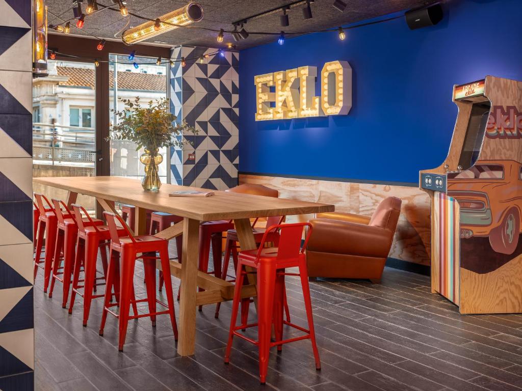 comedor con mesa de madera y taburetes rojos en Eklo Montpellier Centre Gare, en Montpellier