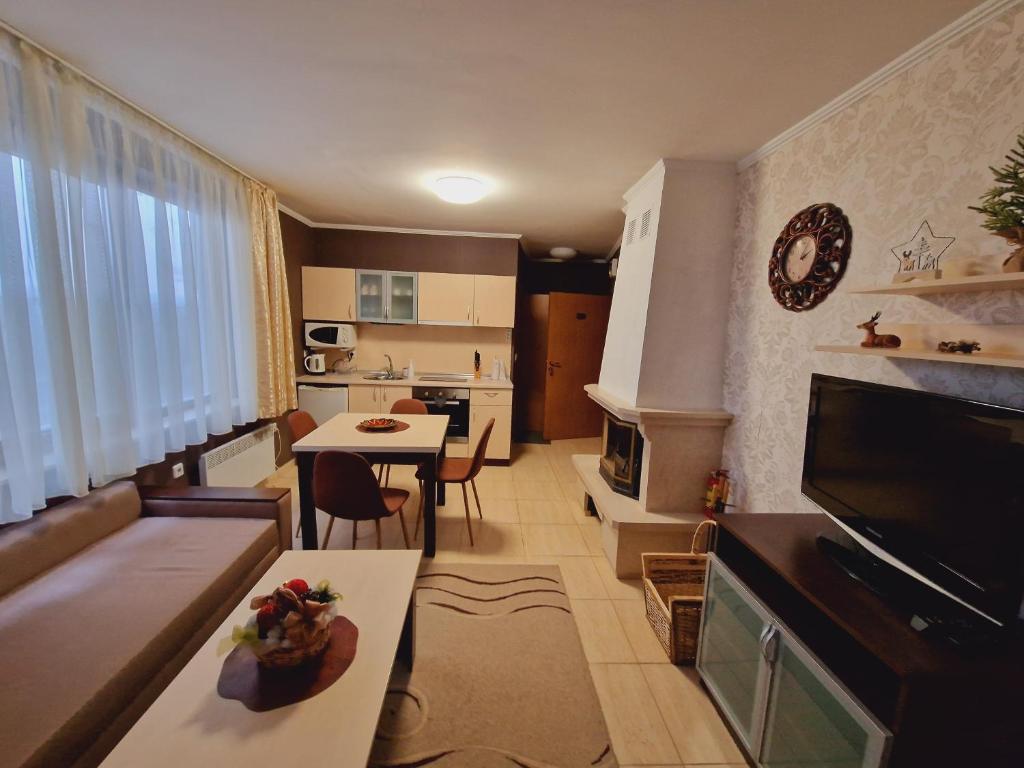 a small kitchen and living room with a table and a couch at апартаменти Уют Гранд Манастира in Pamporovo