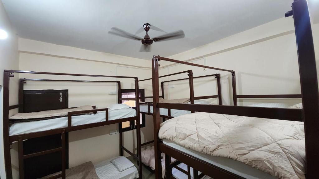a room with three bunk beds and a ceiling fan at Banaras Gully House 500 ft from The Ghats in Varanasi