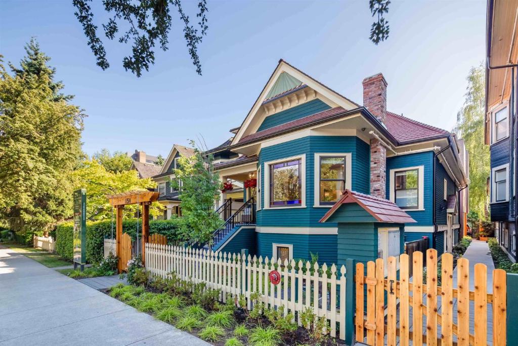 a blue house with a white picket fence at A Gentle Hideaway in the Urban Forest WEST END downtown Vancouver in Vancouver