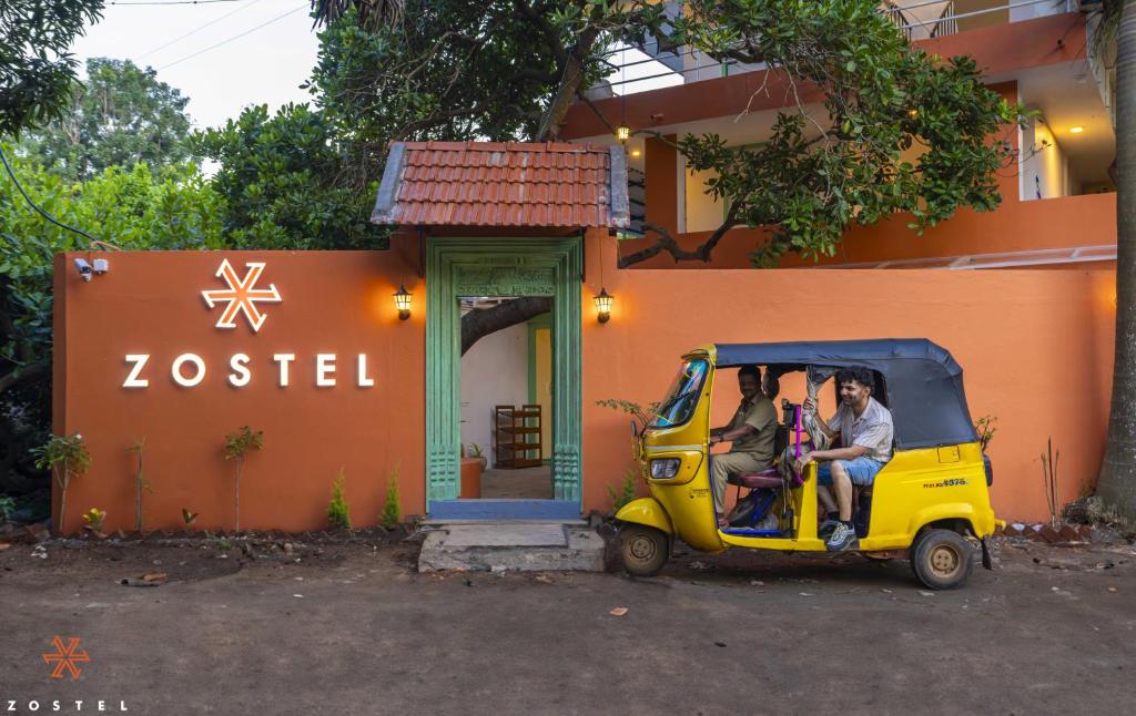 three people sitting in a small car outside a building at Zostel Pondicherry, Auroville Road in Puducherry