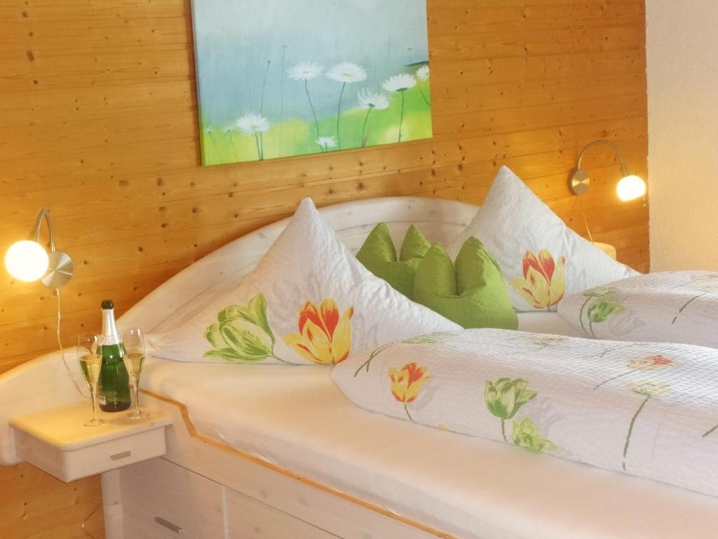 a bedroom with two beds with white sheets and flowers at Landhaus Erna in Böbrach