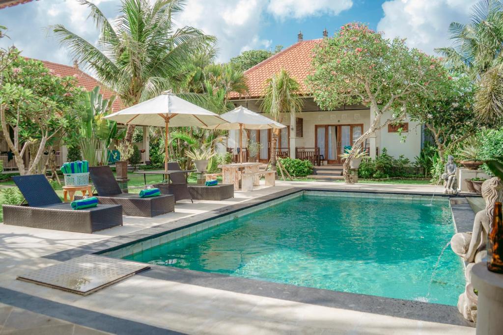 a pool with chairs and umbrellas next to a house at Bingin Garden Uluwatu in Uluwatu