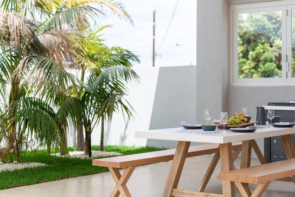a table and benches in a living room with palm trees at The Elements l Air l 4 Stunning Apartments each with Private Outdoor Dining l Walk to the Beach l Event Friendly l Wifi l Netflix l Outdoor Shower l Communal BBQ Pavilion and Lawn Area l in Christies Beach