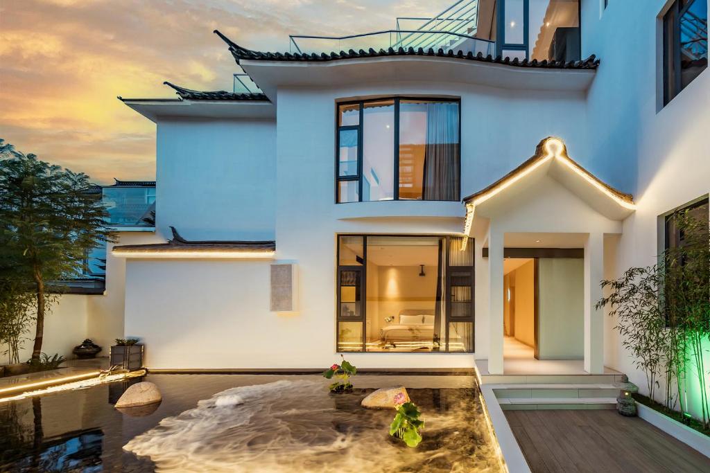 a house with a pond in front of it at Qingdu - LiYuan Hotel in Dali