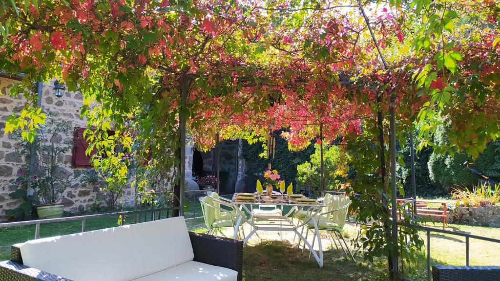 a table and chairs under a tree with flowers at Chambres d&#39;hôtes La Hulotte 69 in Villechenève