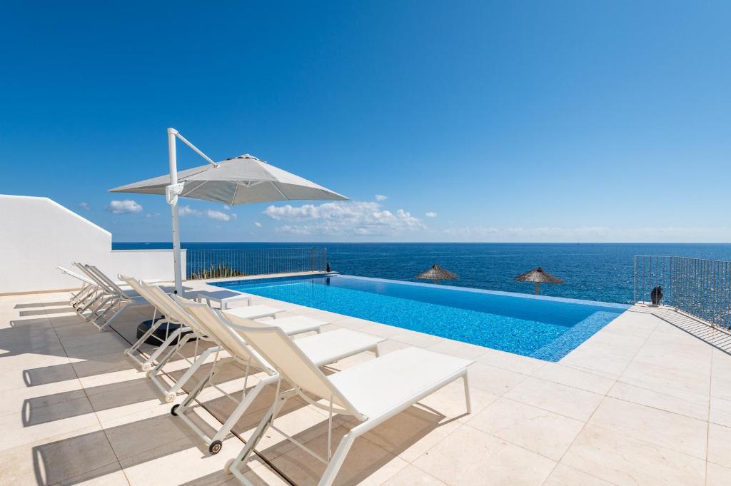 una piscina con sillas y una sombrilla y el océano en Villa Mediterraneo by Mallorca House Rent, en Cala Murada