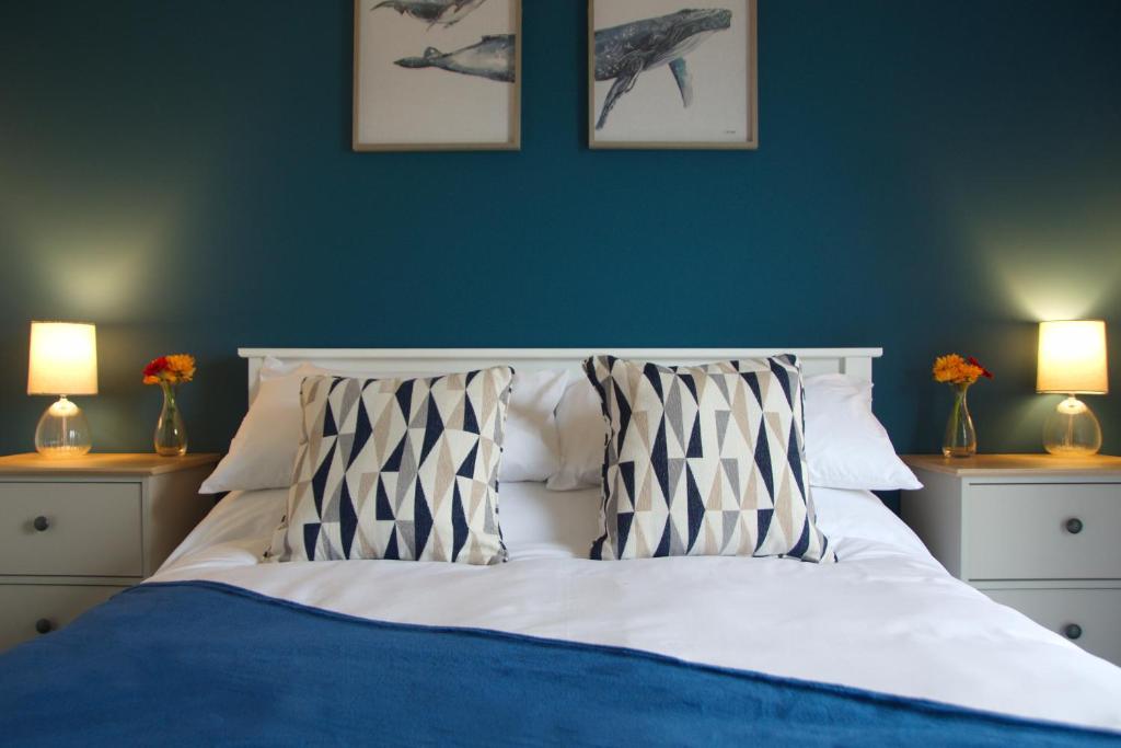 een slaapkamer met een bed met blauwe muren en 2 lampen bij Peedie Picky Townhoose - STL OR00094F in Orkney