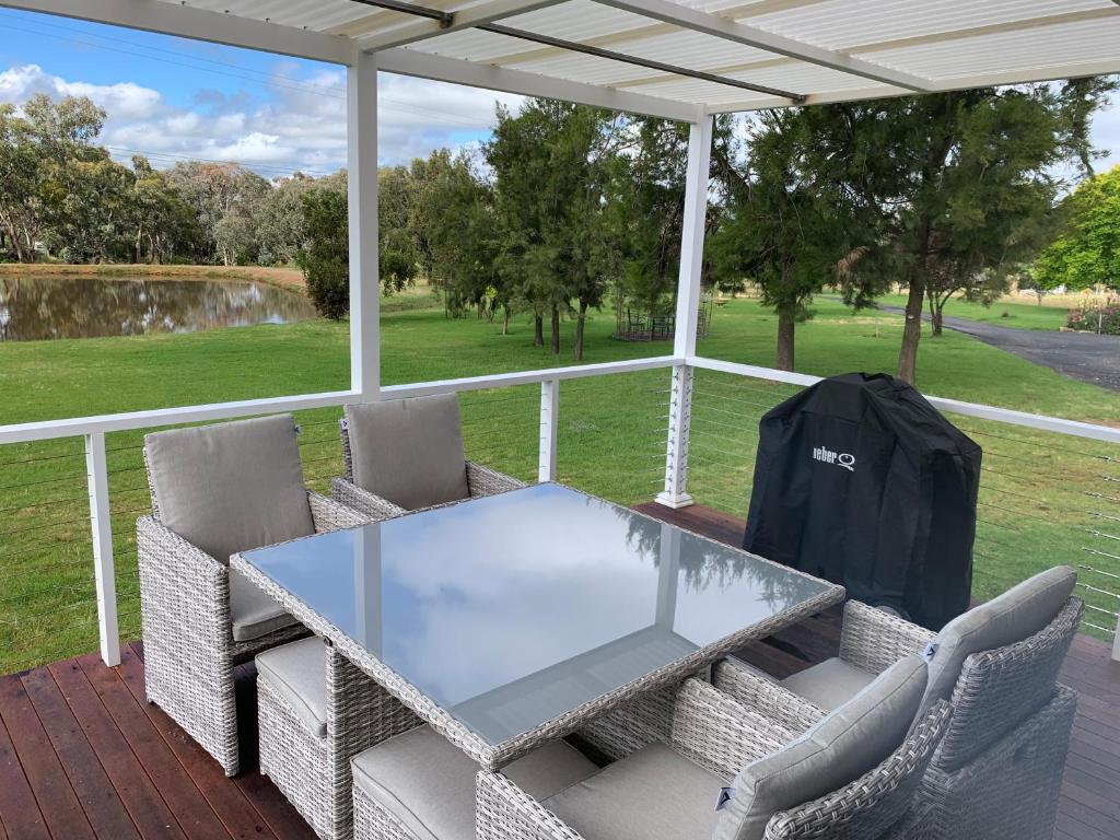 uma mesa de vidro e cadeiras num alpendre em Yarrawonga Cottage em Mudgee