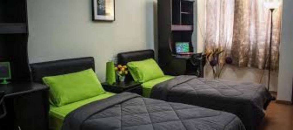 Habitación con 2 camas con almohadas verdes en Worker's Apartman-Munkásszálló, en Igricetanya