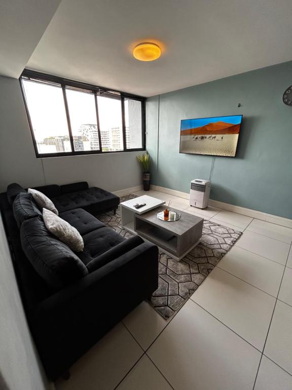 sala de estar con sofá negro y mesa en Cozy Retreat in Windhoek en Windhoek