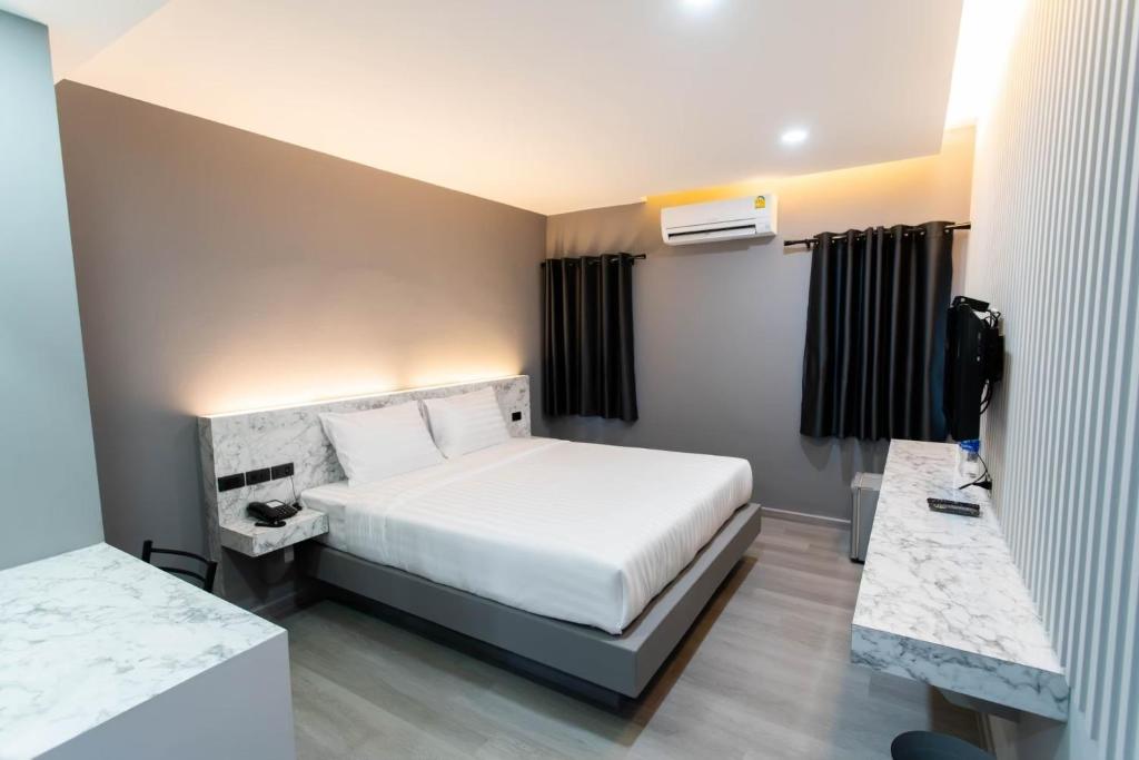 a hotel room with a bed and a television at S3 Hotel (Rayong) in Ban Hua Fat