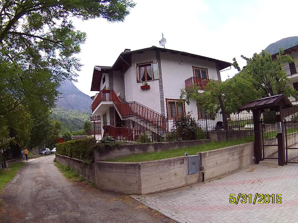 a white house with red railing on a street at Residenza La Ruina in Fenestrelle