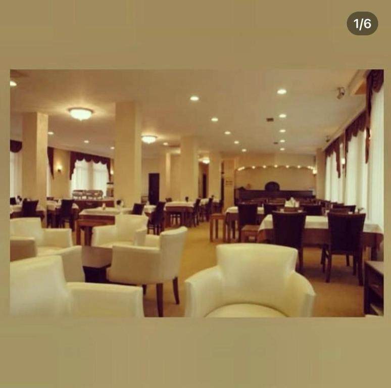 un restaurante con muebles blancos, mesas y sillas en GRAND ADANUS HOTEL, en Seyhan