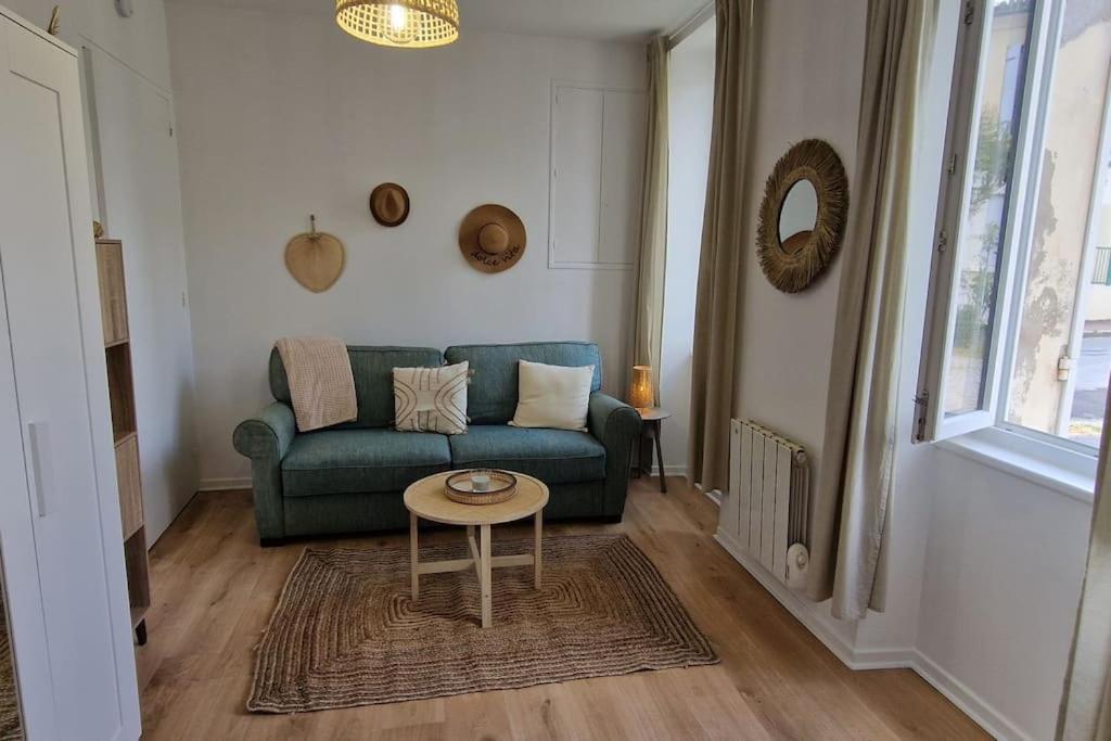 ein Wohnzimmer mit einem grünen Sofa und einem Tisch in der Unterkunft Le Cocon Margalais in Margaux