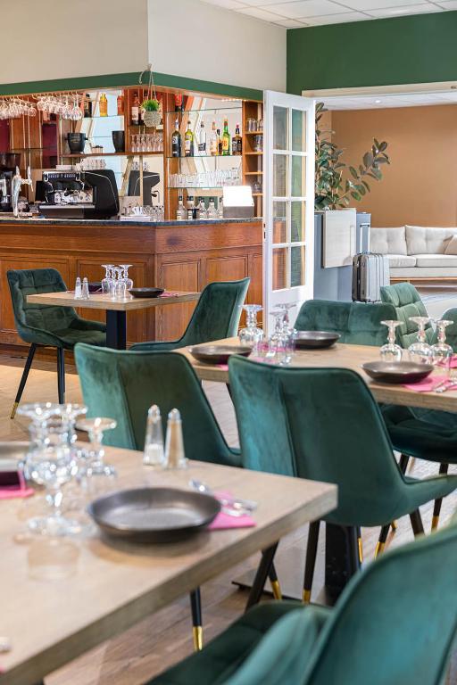 a restaurant with wooden tables and green chairs at Hotel L&#39;Abri in Le Puy-en-Velay