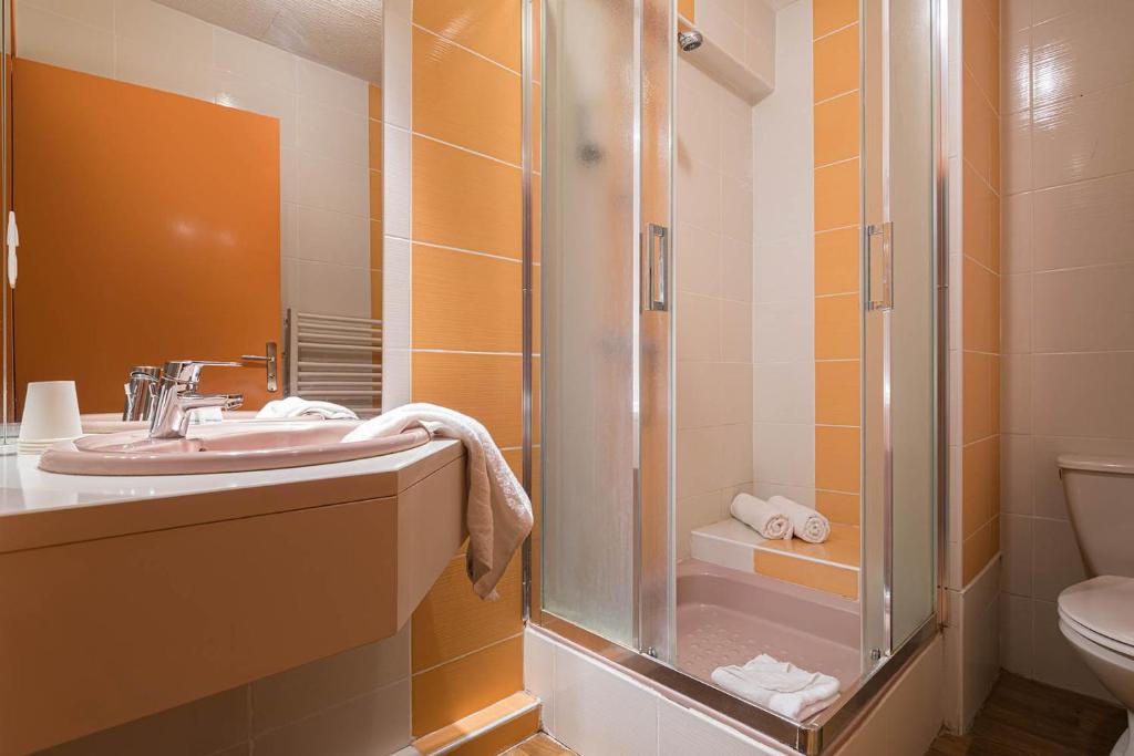 a bathroom with a shower and a sink and a toilet at Hotel L&#39;Abri in Le Puy-en-Velay