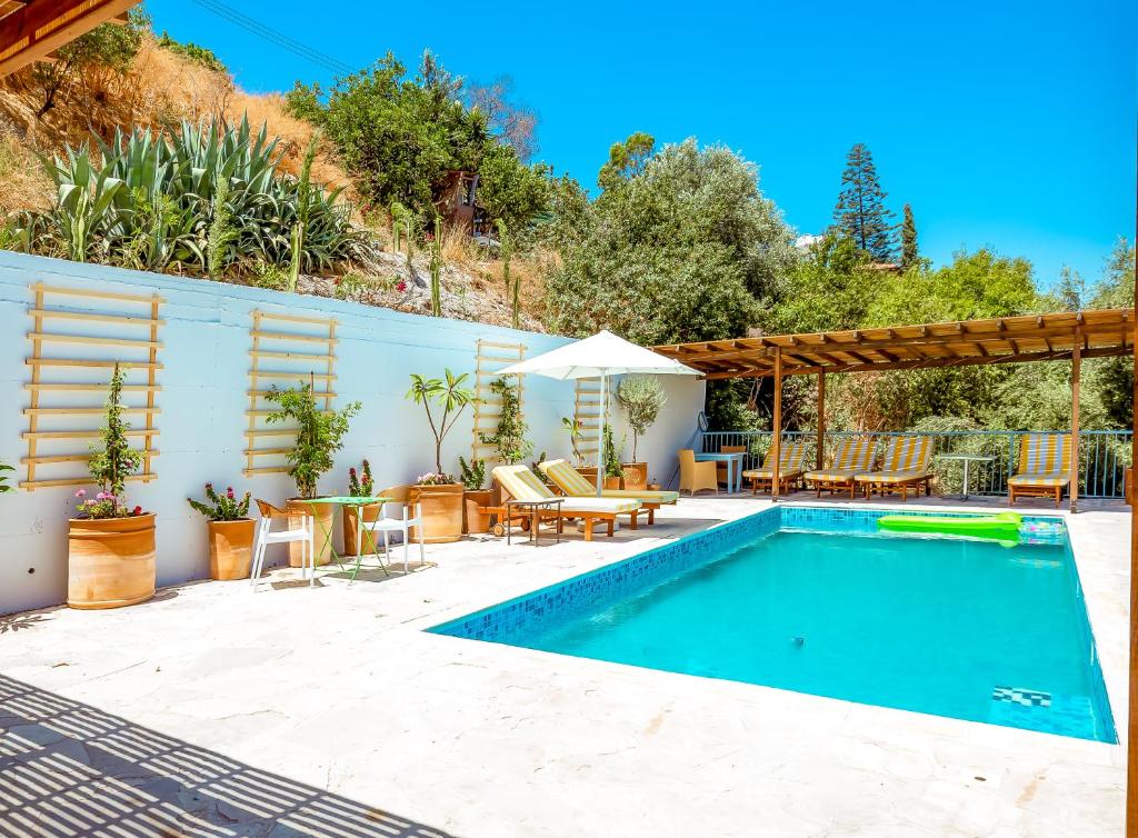 una piscina con mesa, sillas y sombrilla en Archondia House - Holiday Apartments With Pool, en Kalavasos
